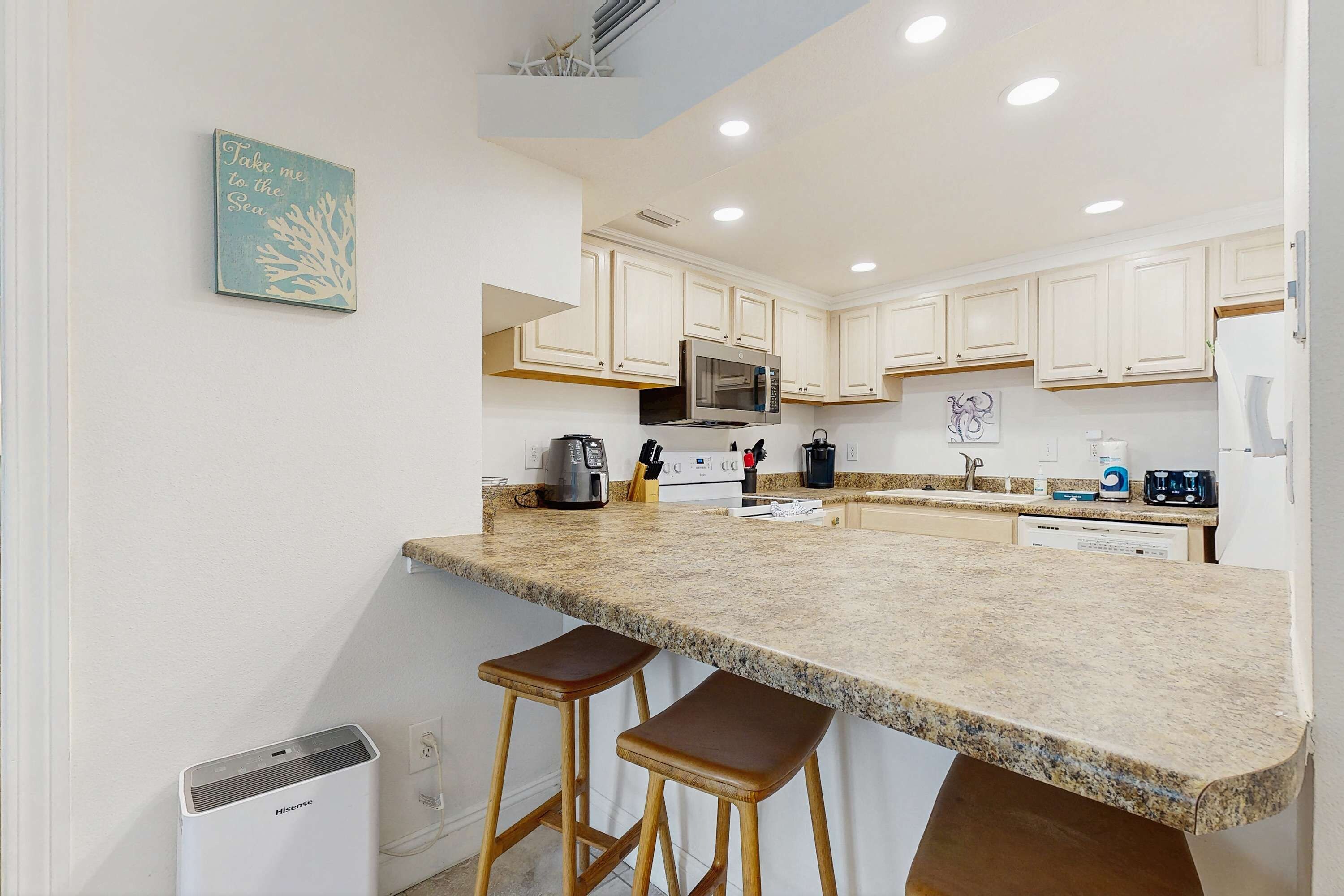 A kitchen with white cabinets, a granite countertop, a microwave, and a sink.