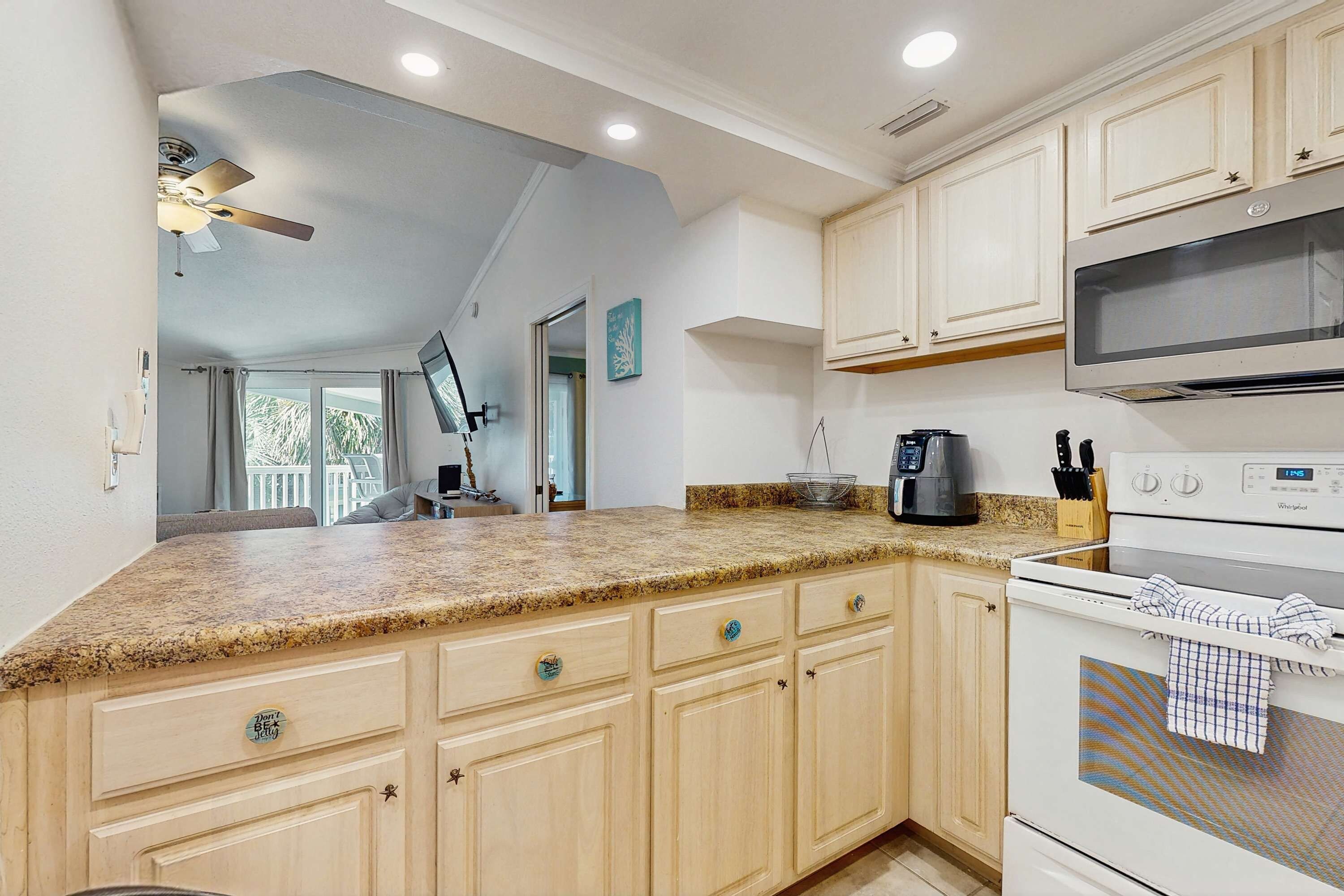 A kitchen with granite countertops, white cabinets, a microwave, and a stove.