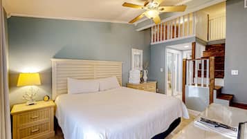 A bedroom with a bed, nightstands, a lamp, a ceiling fan, a staircase, and a door.
