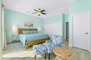 A bedroom with a bed, two chairs, a small table, a ceiling fan, and a door. - Beachfront townhome with ocean views, 2 balconies, W/D, & AC - dog-friendly (Pensacola Beach)