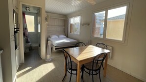 Een kleine slaapkamer met een bed, een plafondventilator en een raam.