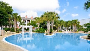 Piscina com espreguiçadeiras e palmeiras.