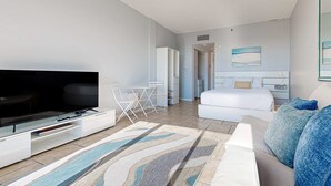 Une chambre d’hôtel moderne équipée d’une télévision à écran plat, d’un canapé, d’un lit et d’un coin repas.
