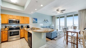 A modern kitchen with wooden cabinets, stainless steel appliances, and a large island with a sink. - Stunning top-floor condo with balcony, pool, & beach access - great location (Fort Walton Beach)