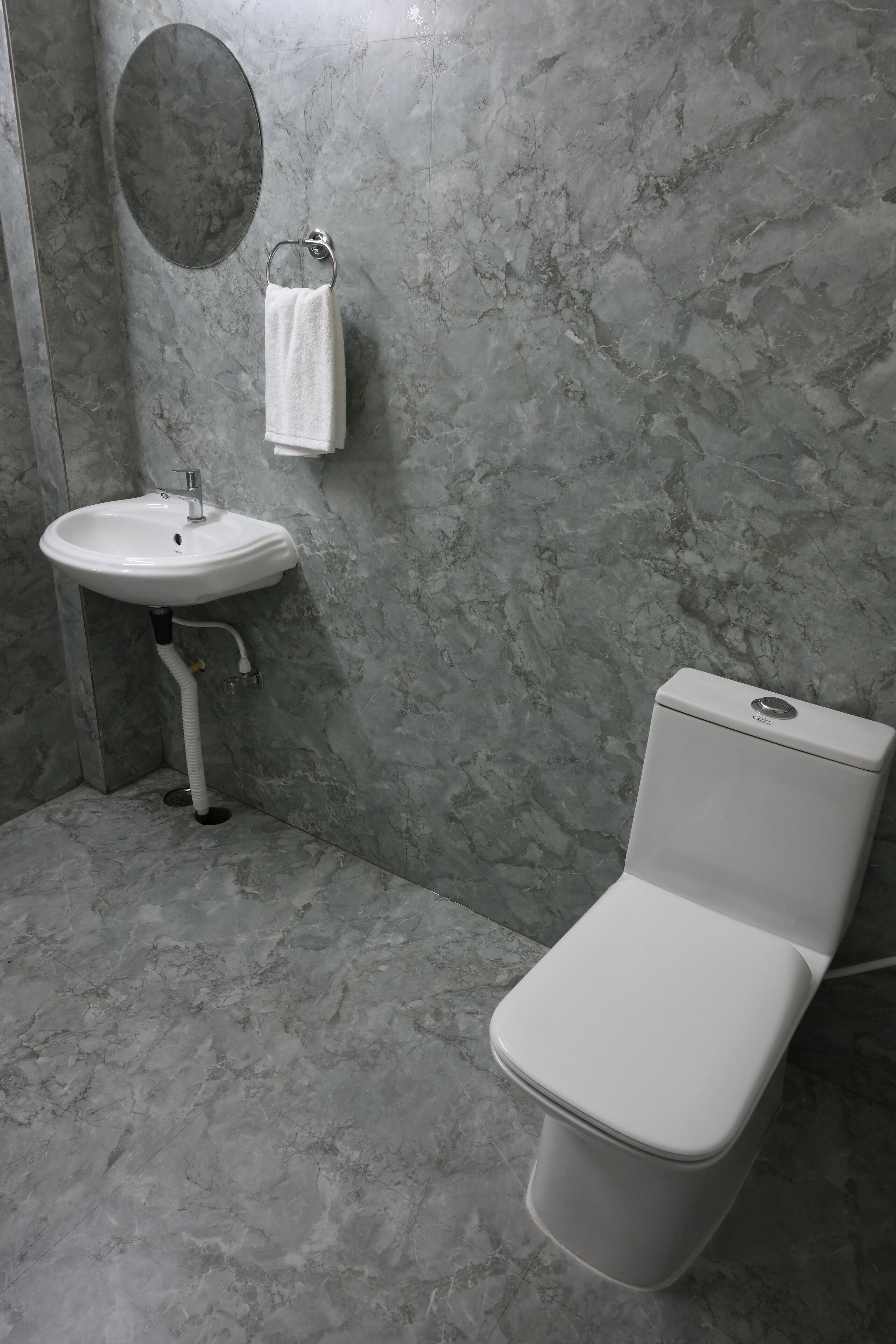 Un baño con lavamanos blanco, inodoro y paredes de mármol.