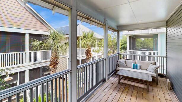 A covered porch with a bench and railing, overlooking a residential area with houses and palm trees. - Beautiful home in a gated community with porches & shared pool,hot tub (Port St. Joe)
