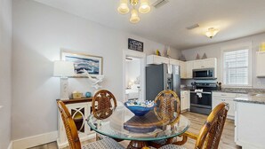 A dining area with a glass table surrounded by wooden chairs with patterned cushions. - Beautiful home in a gated community with porches & shared pool,hot tub (Port St. Joe)