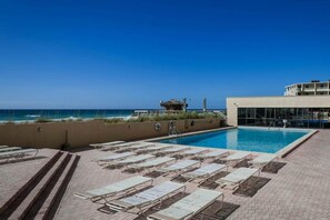 A pool area with lounge chairs and a view of the ocean. - Beach-chic 18th floor condo w gulf-front views Indoor & outdoor pool on-site (Destin)