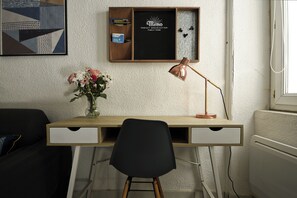 Een modern bureau met een zwarte stoel, een bureaulamp en een vaas met bloemen.