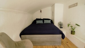 A bedroom with a bed, a chair, a fan, and a potted plant. - Apartment in Aubenas town center, cozy style, office, internet, netflix (Aubenas)