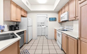 Eine kompakte Küche mit Geschirrspüler, Kühlschrank, Herd, Mikrowelle und einer Kaffeemaschine.