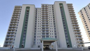 Un immeuble résidentiel à plusieurs étages, doté d’une entrée centrale et de balcons.