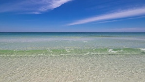 Ein Strand mit klarem, flachen Wasser und blauem Himmel.