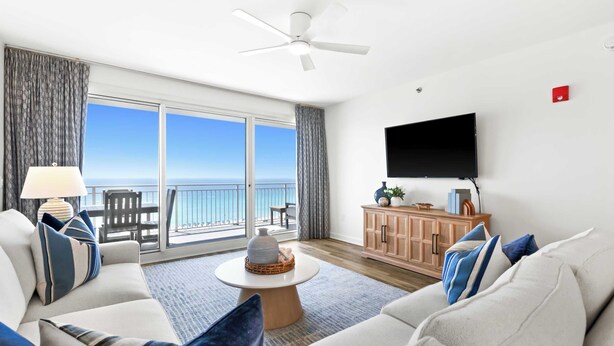 Ein Wohnzimmer mit Sofa, Couchtisch, Fernseher und einem Balkon mit Meerblick.