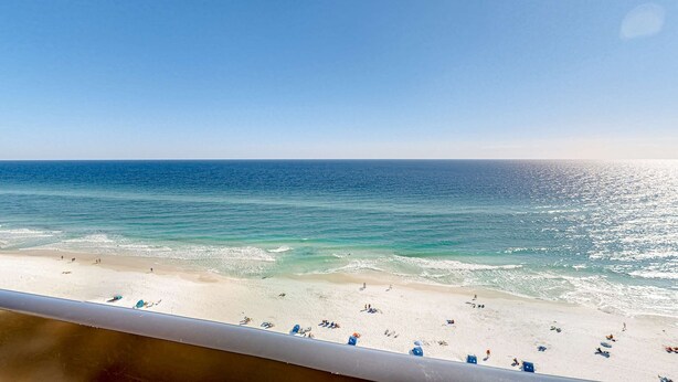 A beach view from a balcony with a railing, clear sky, and calm sea. - Spacious oceanfront condo with pool on-site, ocean view, WiFi & central AC (Destin)