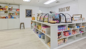 A coffee shop interior with a 'BREW' sign, shelves stocked with various products, and a chalkboard menu. - Beachfront Escape with Gulf Views, Pool & Hot Tub (Destin)