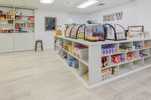 Ein Café-Interieur mit einem 'BREW'-Schild, Regalen voller verschiedener Artikel und einer Kreidetafel-Speisekarte.