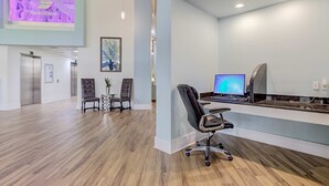 A modern office space with a wooden floor, a desk with a computer, two chairs, and an elevator in the background. - Beachfront Escape with Gulf Views, Pool & Hot Tub (Destin)