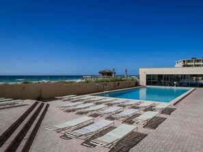 A pool area with lounge chairs and a view of the ocean. - Beachfront Escape with Gulf Views, Pool & Hot Tub (Destin)