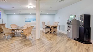 A room with a wooden floor, a dining table with chairs, a refrigerator, and a cash register. - Beachfront Escape with Gulf Views, Pool & Hot Tub (Destin)