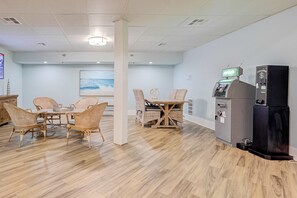 Ein Zimmer mit Holzboden, einem Esstisch mit Stühlen, einem Kühlschrank und einer Registrierkasse.