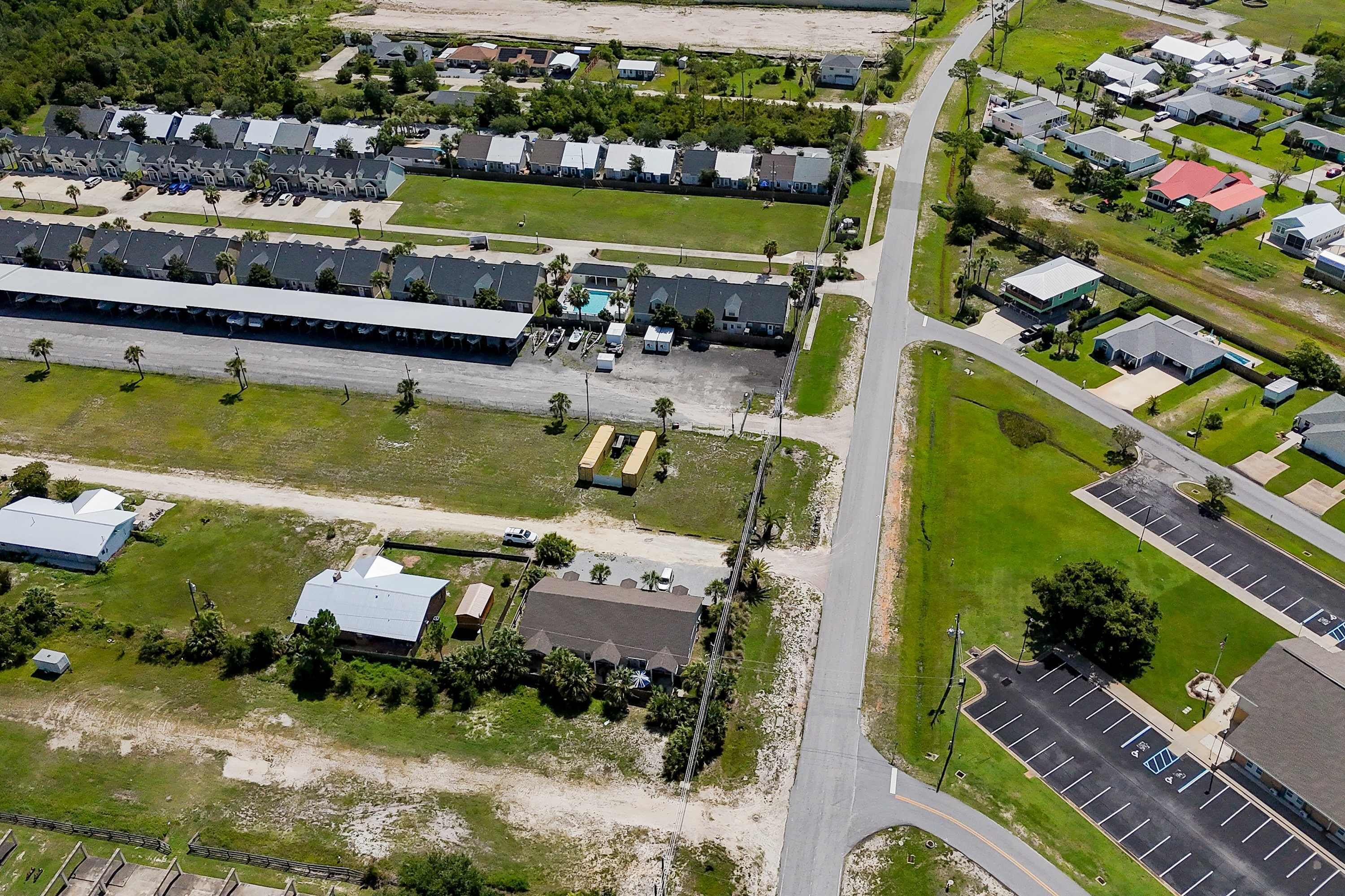 Vista aérea de una zona residencial con varias casas, un estacionamiento grande y algunos edificios con techos planos.