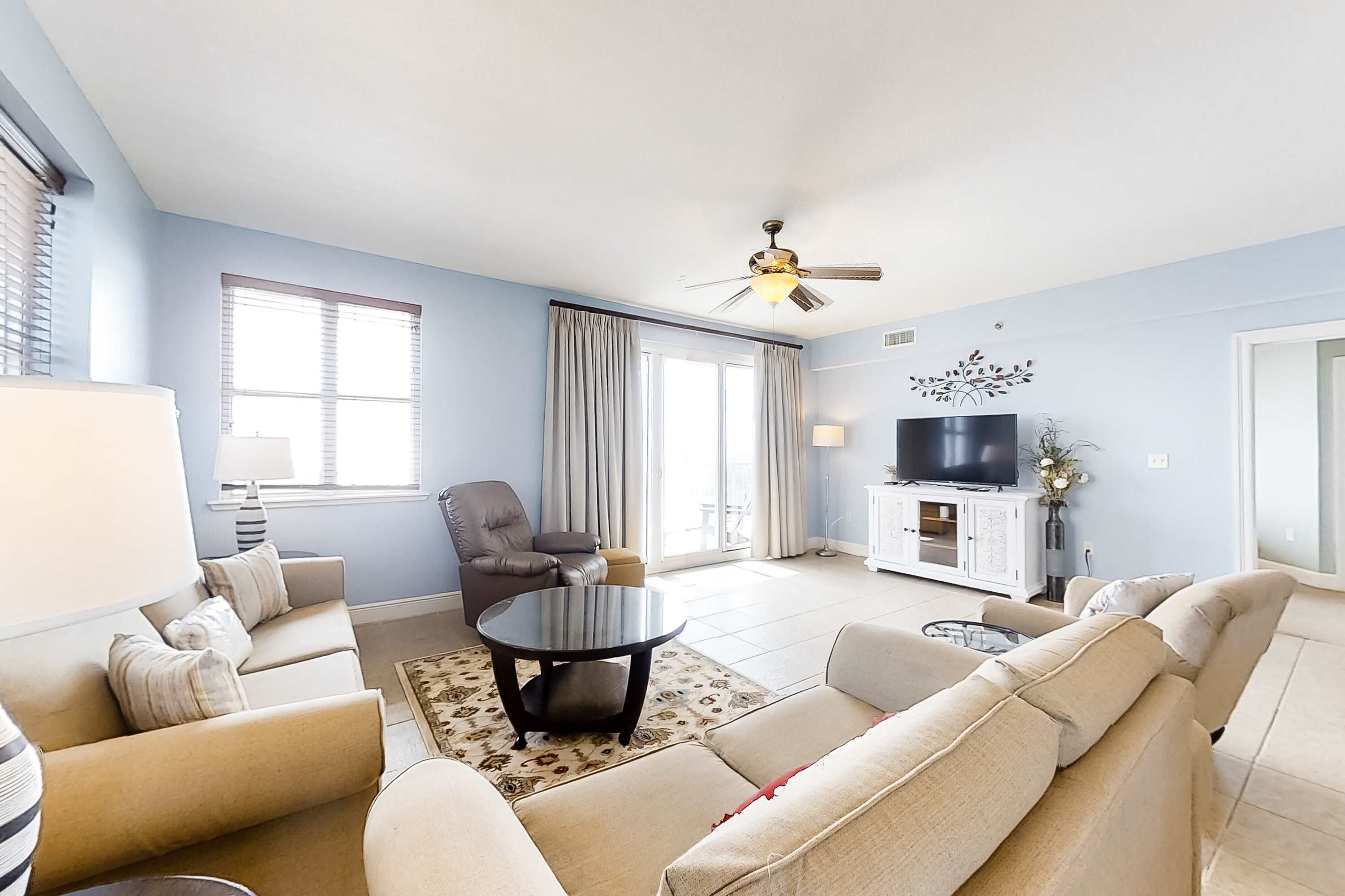A living room with a sofa set, a coffee table, a TV, and a ceiling fan.