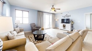 A living room with a sofa set, a coffee table, a TV, and a ceiling fan. - Spacious 3 Bedroom Condo with Beach Views and Resort Pool Access (Miramar Beach)