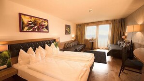 A hotel room with two beds, a sofa, a desk, and a view of the outdoors. - Hotel Rettenberg (Kolsass)