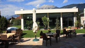 A modern outdoor patio with stone flooring, outdoor furniture, and potted plants. - Hotel Rettenberg (Kolsass)
