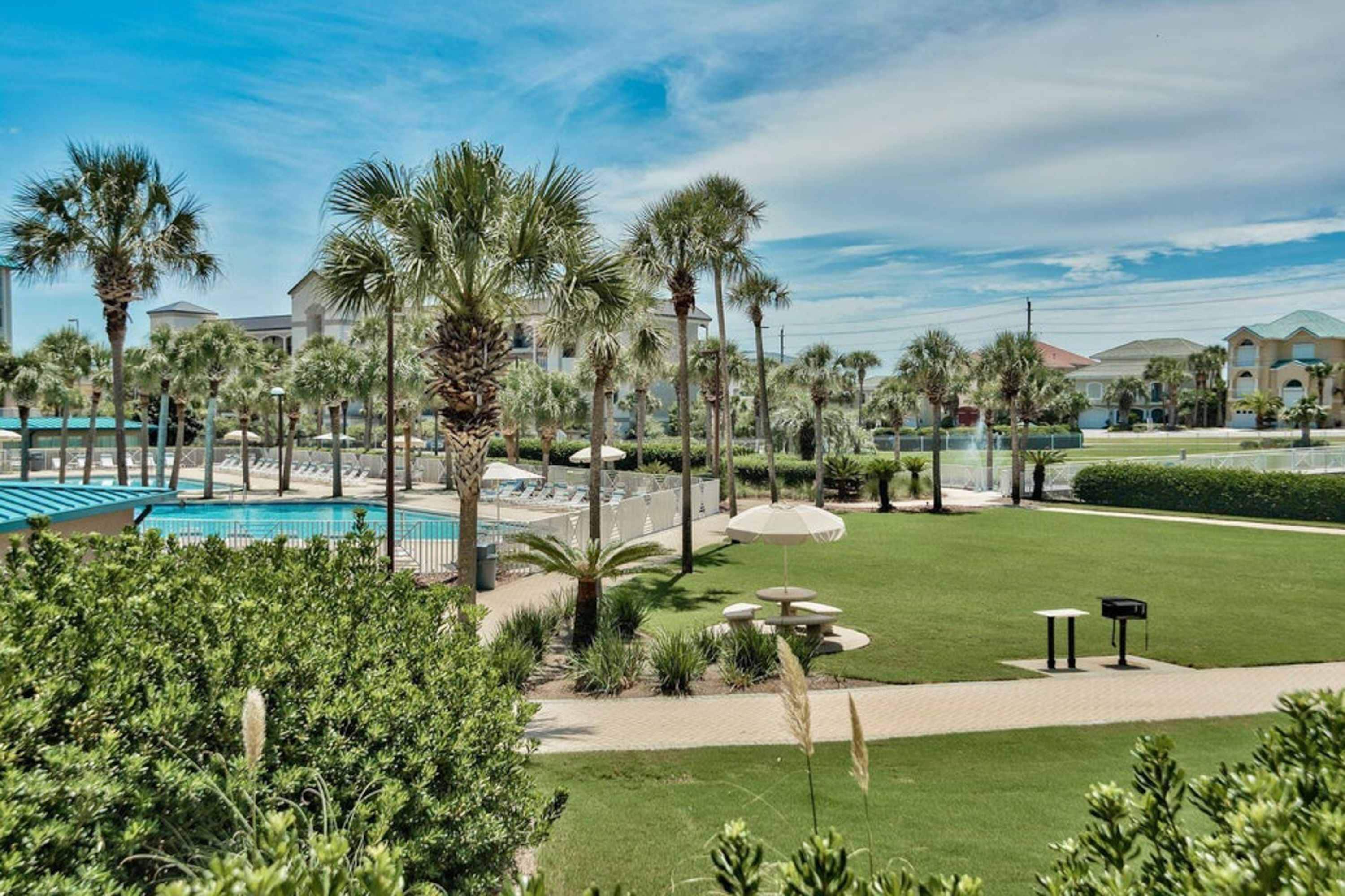 Ein Resort mit Poolbereich, Palmen und einem gepflegten Rasen.