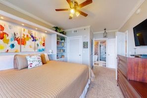 A bedroom with a bed, a ceiling fan, a TV, and a bookshelf. - Idyllic beach getaway w gulf views & swimming pool - beach access (Destin)