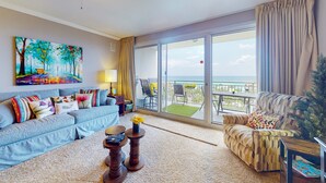 A living room with a sofa, armchair, and a painting on the wall. - Idyllic beach getaway w gulf views & swimming pool - beach access (Destin)