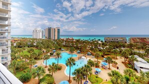A resort with a central pool, palm trees, and a view of the ocean. - Idyllic beach getaway w gulf views & swimming pool - beach access (Destin)
