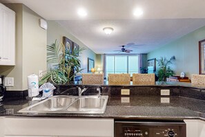 A kitchen with a double sink, a dishwasher, and a ceiling fan. - Beachfront condo rental with pools, hot tub, and private balcony (Panama City Beach)