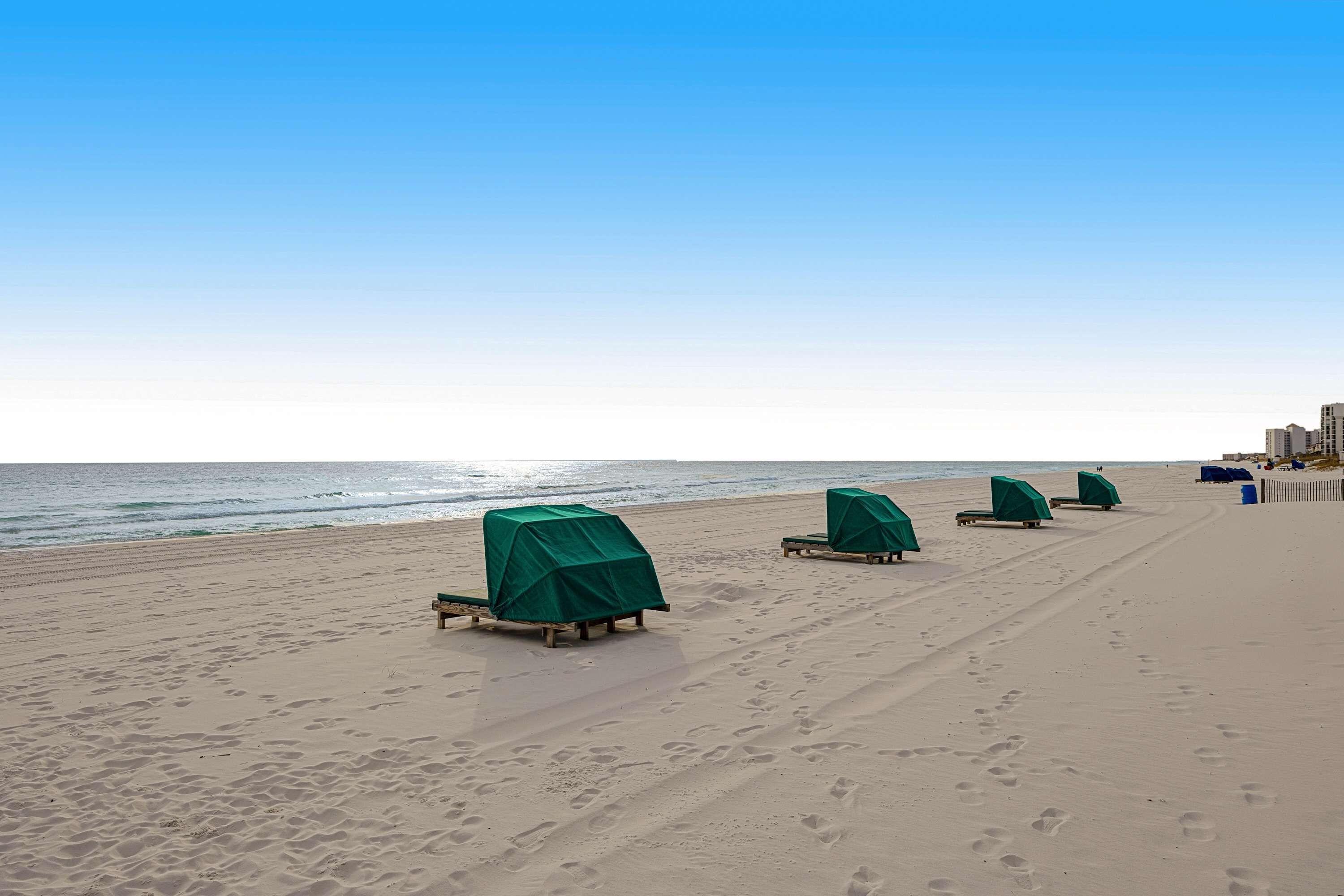 Una playa con hileras de sillas de playa cubiertas y una vista despejada del océano.