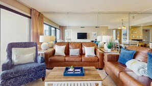 Ein modernes Wohnzimmer mit einem braunen Ledersofa, einem gemusterten Sessel und einem Couchtisch mit einer blauen Ablage.
