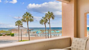 Un balcone con vista sulla spiaggia, palme e area piscina.