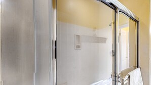Ein Badezimmer mit Duschkabine aus Glas, Handtuchhalter und sichtbarem Bedienfeld für die Dusche.