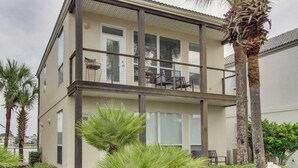 Un edificio de dos pisos con un balcón, palmeras y un cartel que indica 'Ocean Reef Destiny 6'.