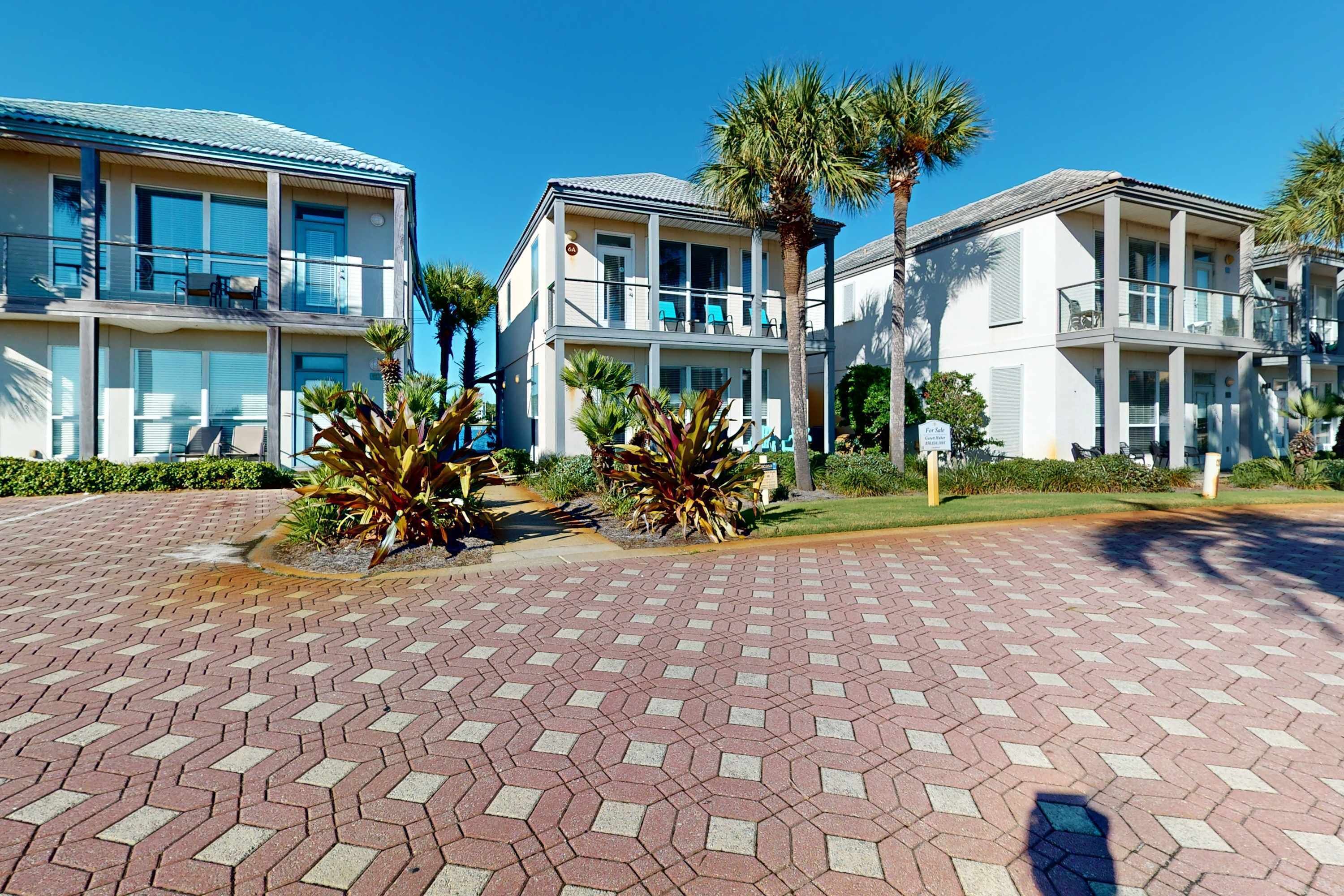 A multi-story hotel with balconies, palm trees, and a paved walkway.