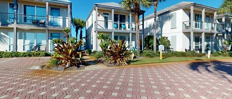 A multi-story hotel with balconies, palm trees, and a paved walkway.