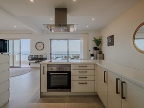 Eine moderne Küche mit Backofen, einem großen Fenster mit Meerblick und einem Essbereich.