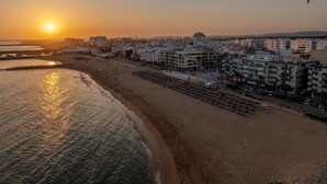 A coastal cityscape with a beach, buildings, and a sunset. - T2 Sunrise Dream-frente MAR (Loulé)