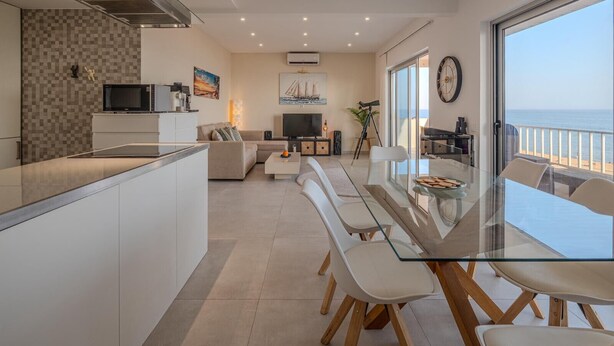 A modern apartment with a kitchen, living area, and balcony with a view of the sea. - T2 Sunrise Dream-frente MAR (Loulé)