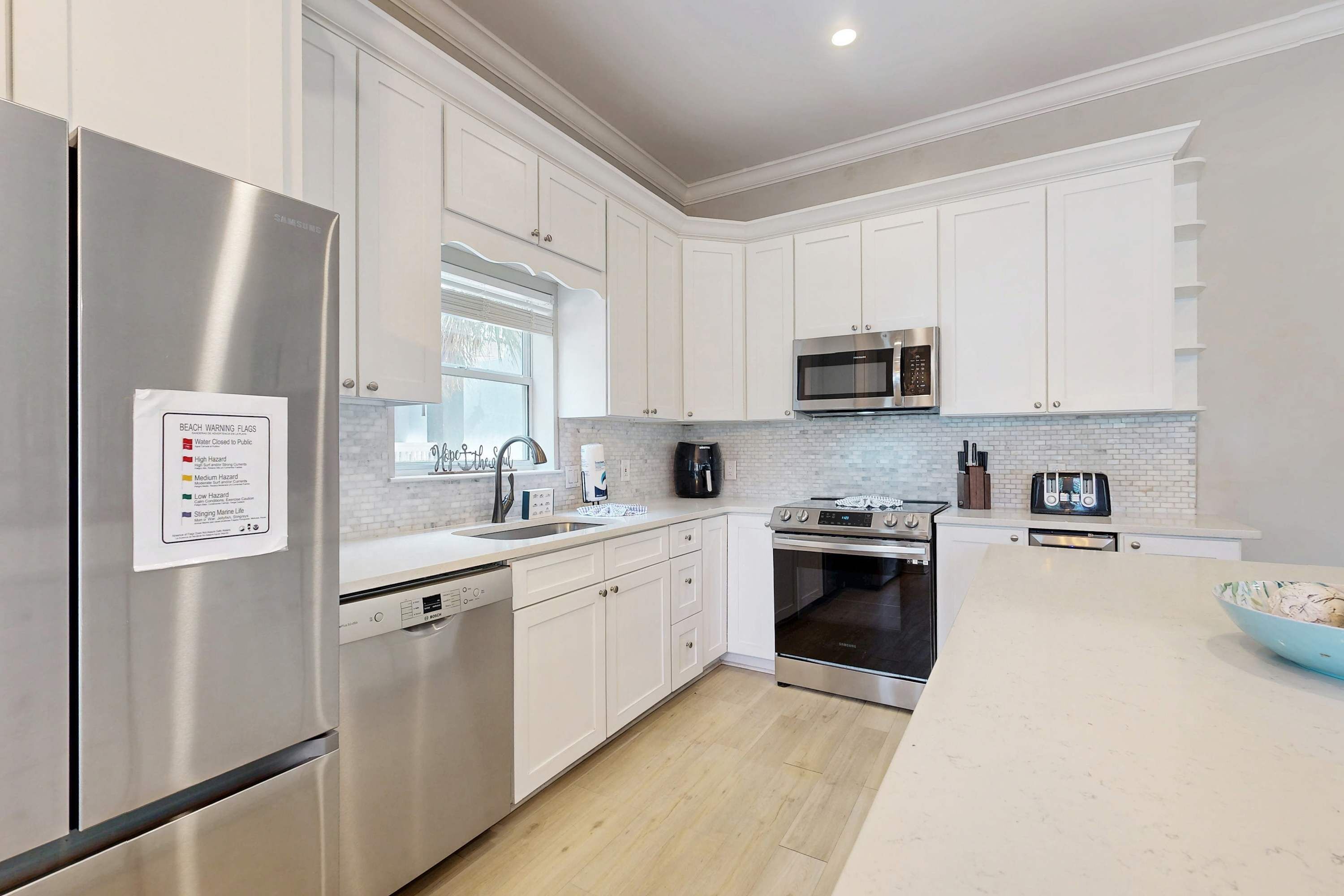 A modern kitchen with white cabinets, stainless steel appliances, a microwave, oven, and a dishwasher.