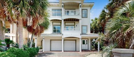 A multi-story building with a symmetrical facade, multiple balconies, and a paved driveway.