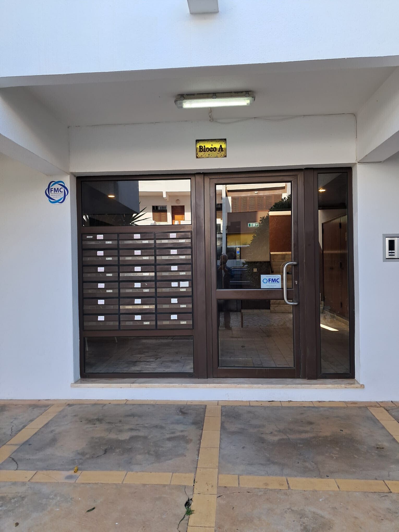 A building entrance with a sign reading "Bloco A" and a "FMC" sign on the wall.