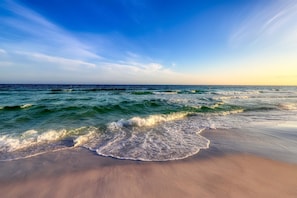 A beach with waves gently lapping onto the shore under a clear sky. - Crystal Beach Subdivision - Sea Glass Cottage (Destin)