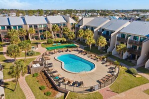 A resort with a large pool, multiple balconies, and palm trees. - Three-story condo in beachfront complex with patios, balconies, pool & hot tub (Panama City Beach)